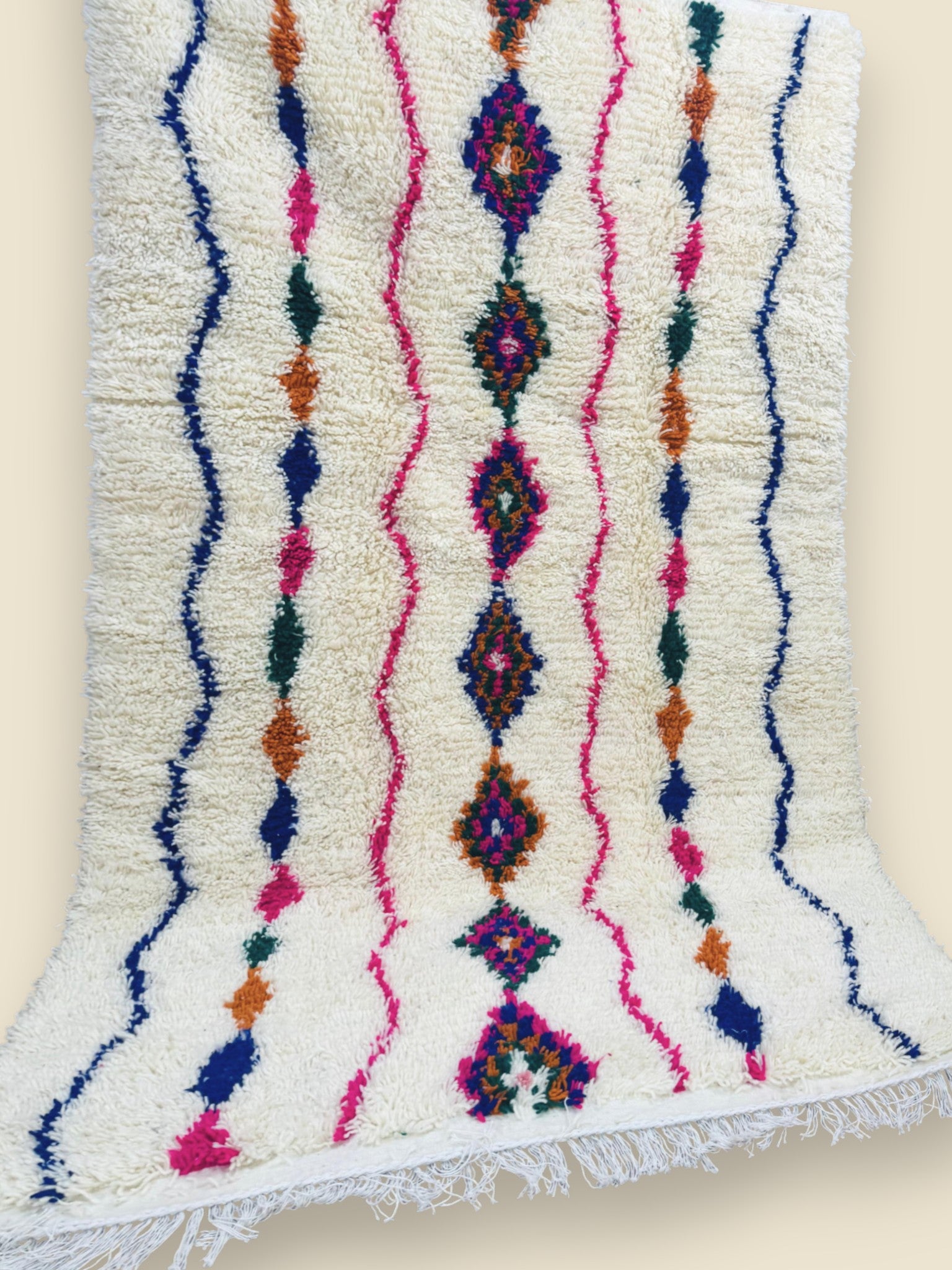 Handwoven Moroccan Tiziriwen rug displayed vertically against wall