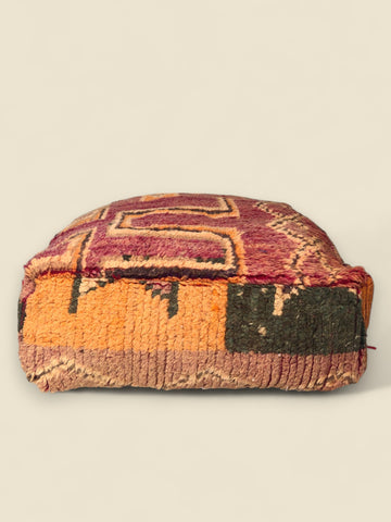 Side view of Tizwit Moroccan pouffe showing worn rug patterns in earthy colors