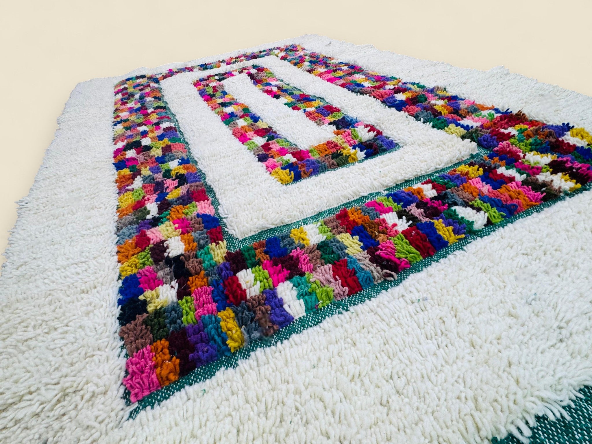 Handwoven wool rug with bright checkered design and ivory base.