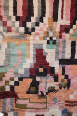 Close-up of geometric Berber patterns with rust, peach, green, and black wool