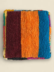 Top view of Asmoun Moroccan pouffe with vibrant orange, blue, and burgundy wool panels