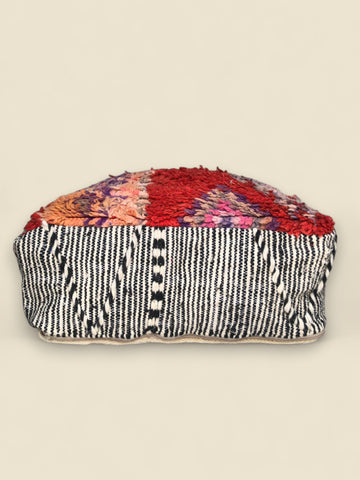 Side view of Tislit pouffe showing black-and-white striped kilim fabric with soft wool top.