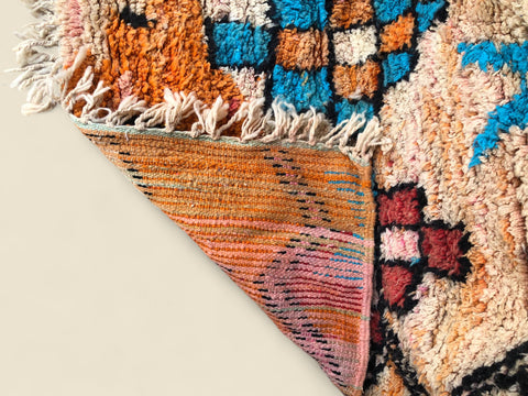 Close-up of a colorful patterned rug corner on a neutral background
