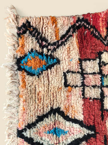 Close-up of a colorful woven rug with geometric patterns on a beige background