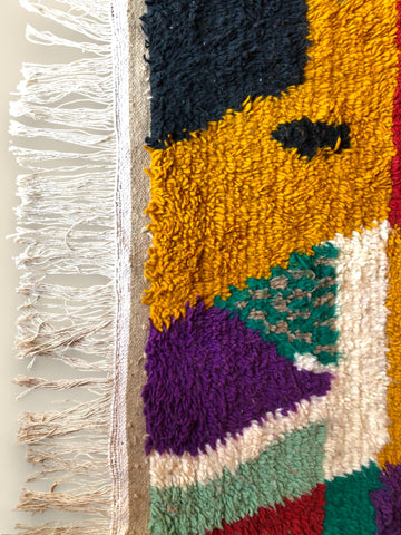 Close-up of Asalas Moroccan rug fringe and wool pile in mustard and black