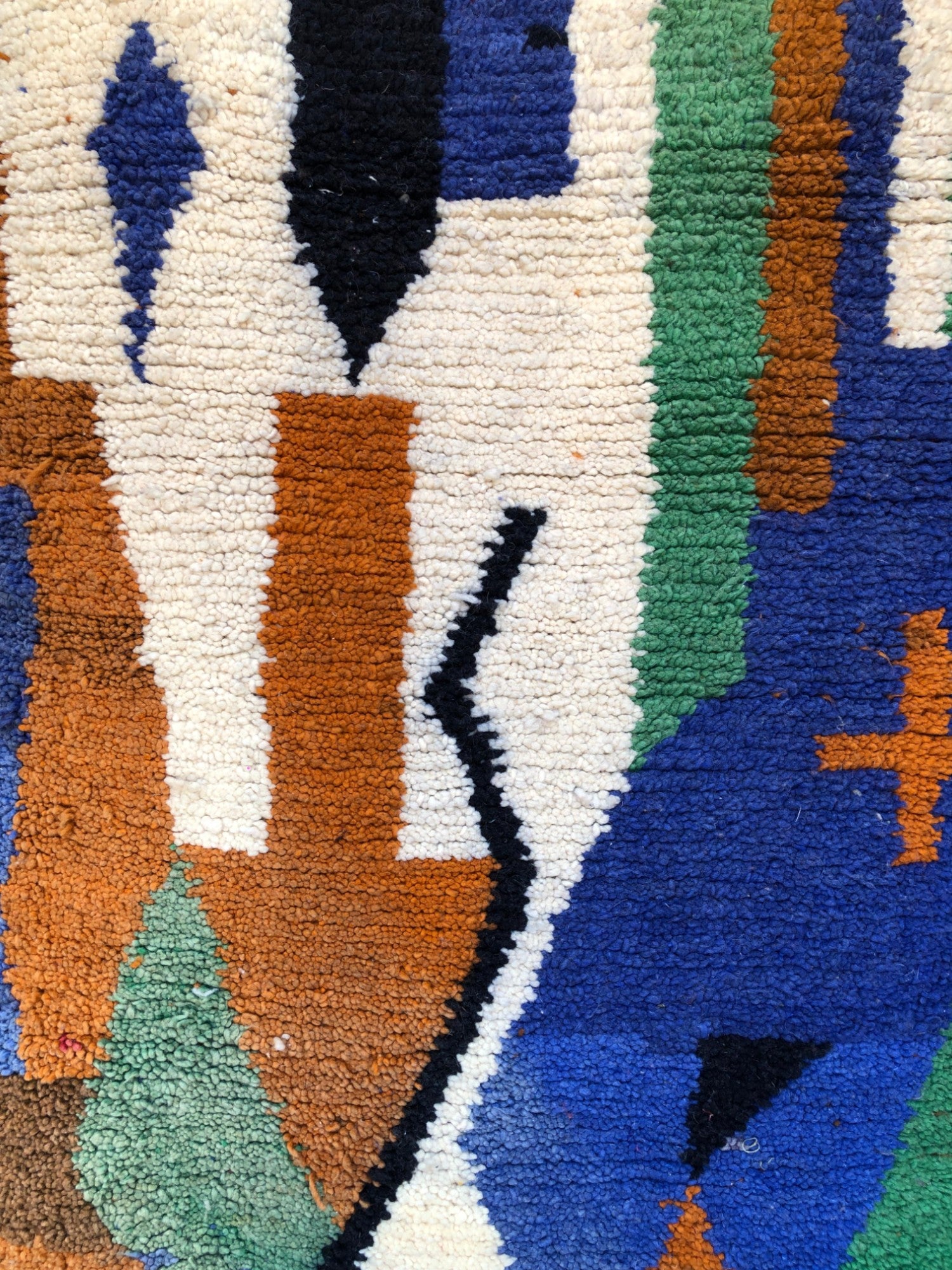 Detailed pattern with black zigzag and colorful motifs in white, brown, green, and blue wool.