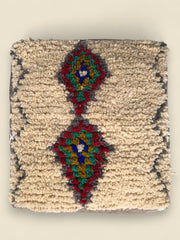 Top view of Yanna Moroccan Berber pouffe with colorful diamond motifs on cream wool