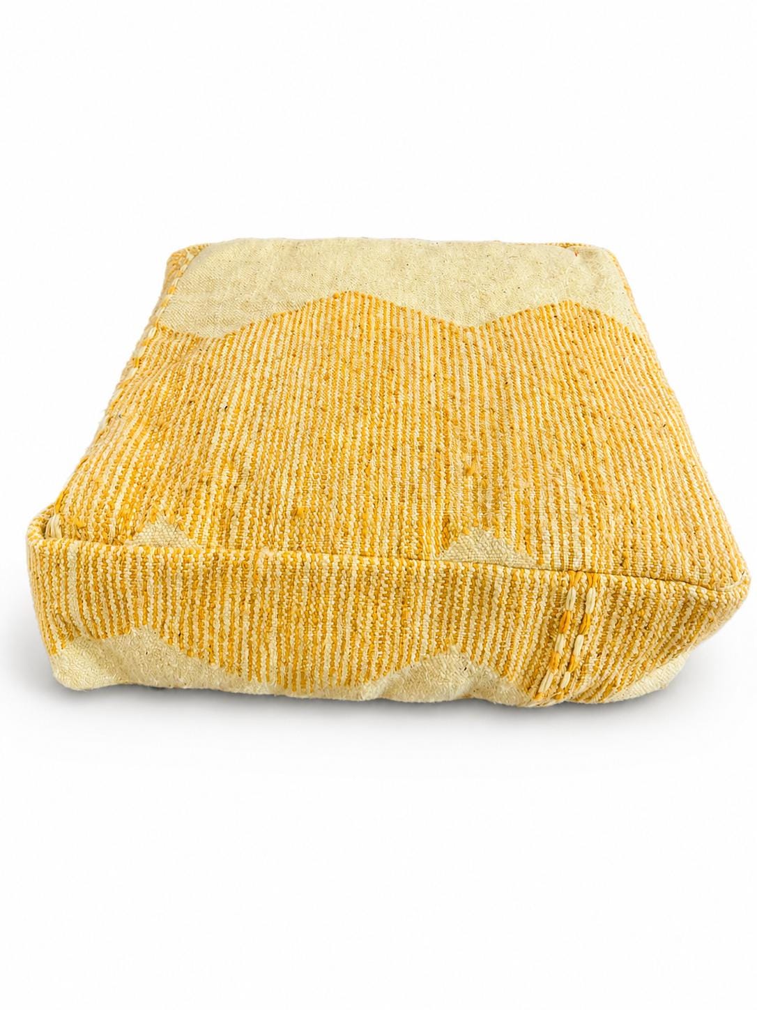 Handmade mustard Moroccan Berber wool pouf isolated on a white background.