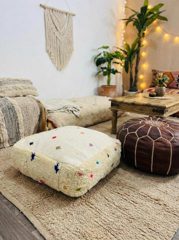 Cream Moroccan Berber pouf with colorful tufted details in cozy boho living room
