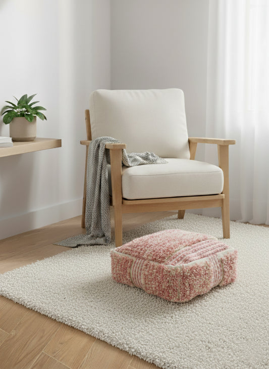 Pink and white handmade Berber wool pouf used as a floor cushion in a cozy modern living room.