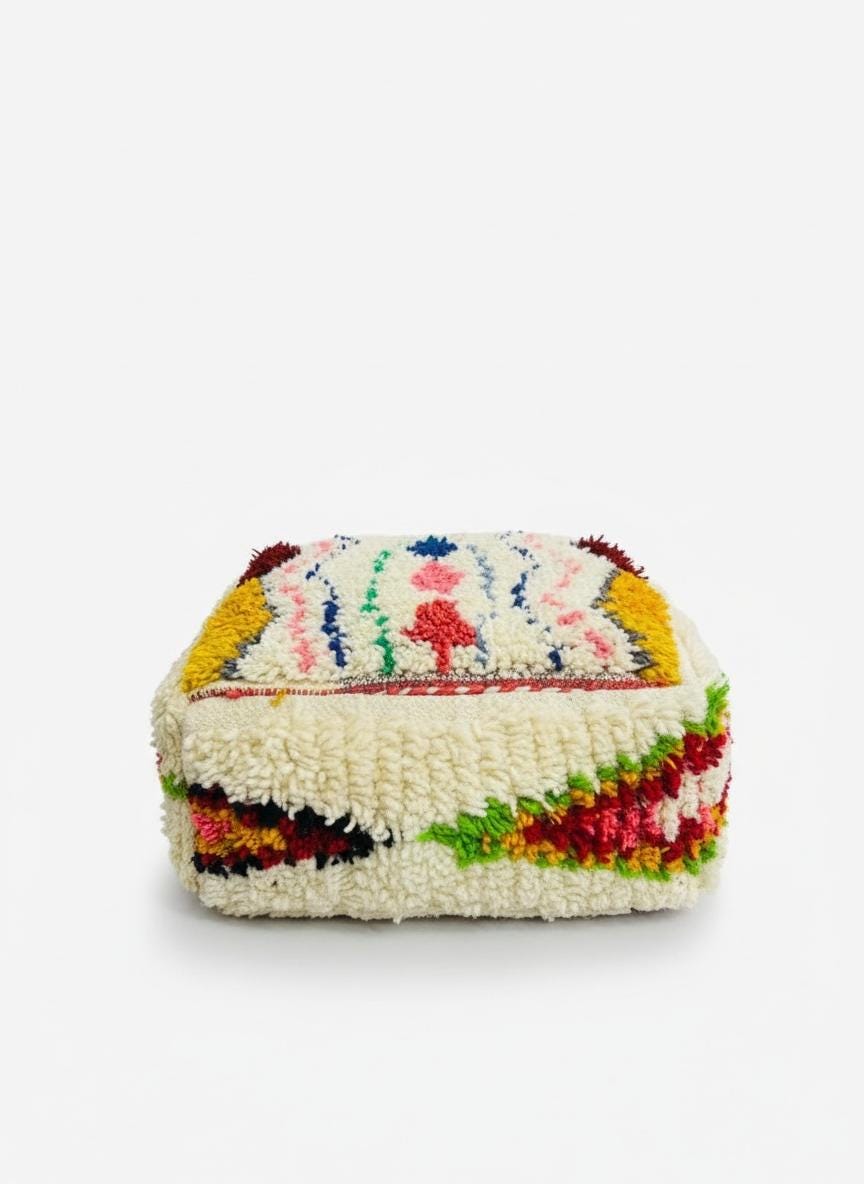 Cream Berber pouf with vibrant geometric sides on white background.