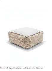 Handmade beige wool pouf with zipper underside, soft sherpa-style texture.