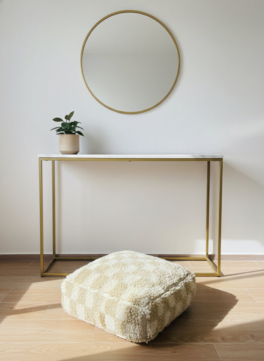 “Beige and cream checkered Berber pouffe in modern entryway.”