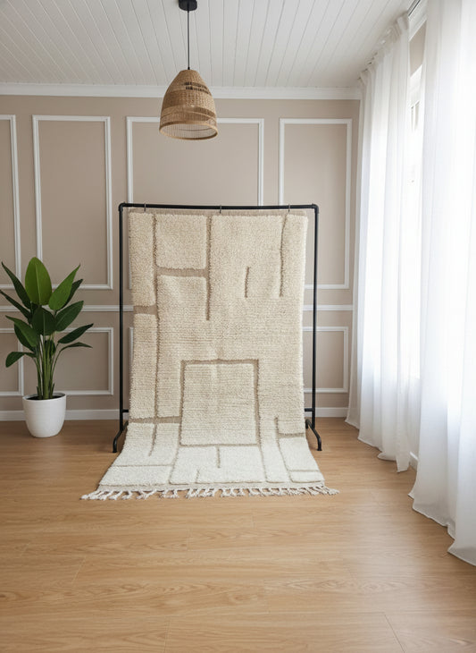 Berber Yuba rug displayed upright showing its cream wool texture and geometric lines.