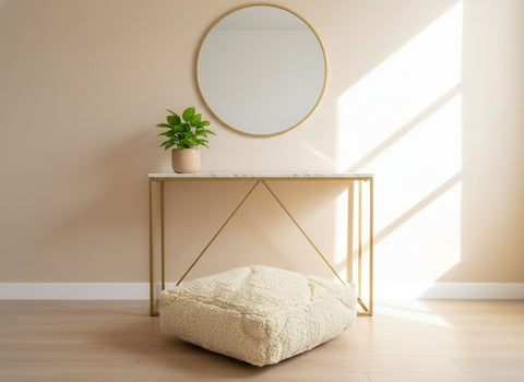 Neutral beige pouf placed under a console table with minimalist home décor
