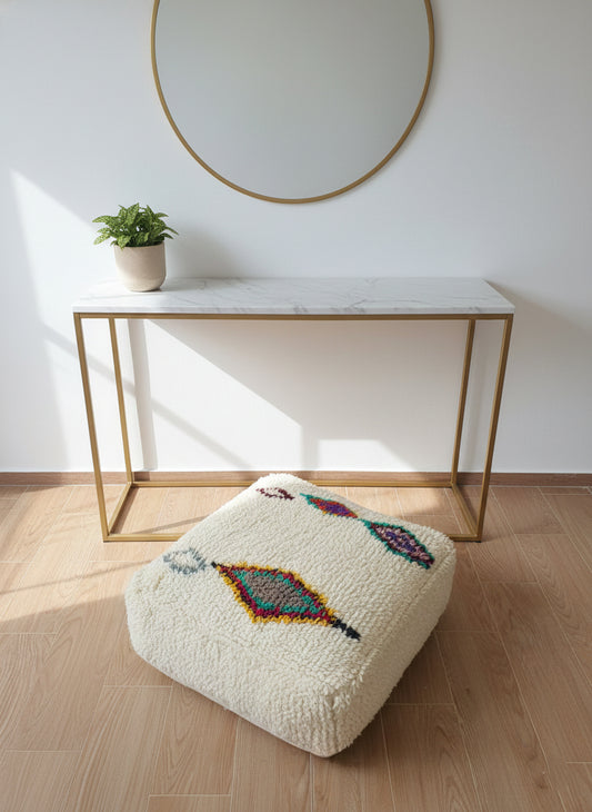 Handwoven Amnay pouf with colorful motifs in sunlight.