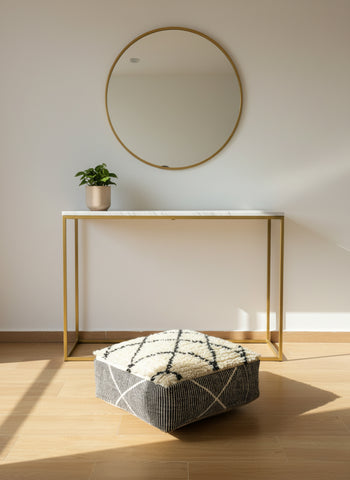 Moroccan wool pouf displayed under a modern console table in natural light.