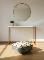 Moroccan wool pouf displayed under a modern console table in natural light.