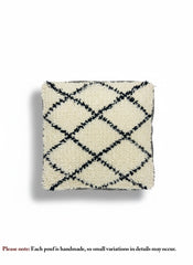 Top view of a handmade beige and black diamond-pattern Moroccan pouf.