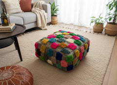 Multicolor Moroccan pouffe under a console table in a sunlit room.