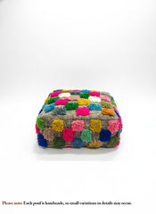 Front view of Berber Ider pouffe with bright wool tufts on a white background.
