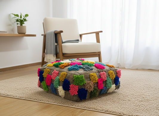 Colorful Moroccan Berber Ider pouffe on a beige rug in a bright room.