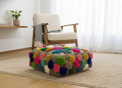 Colorful Moroccan Berber Ider pouffe on a beige rug in a bright room.