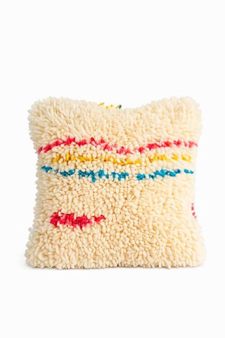 Close-up of a handmade Moroccan Berber wool pillow with colorful pink, yellow, and blue tribal accents on a white background.