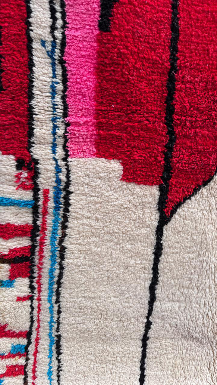 Close-up of the red, pink, and blue woven details on the handmade Tisili Berber rug.