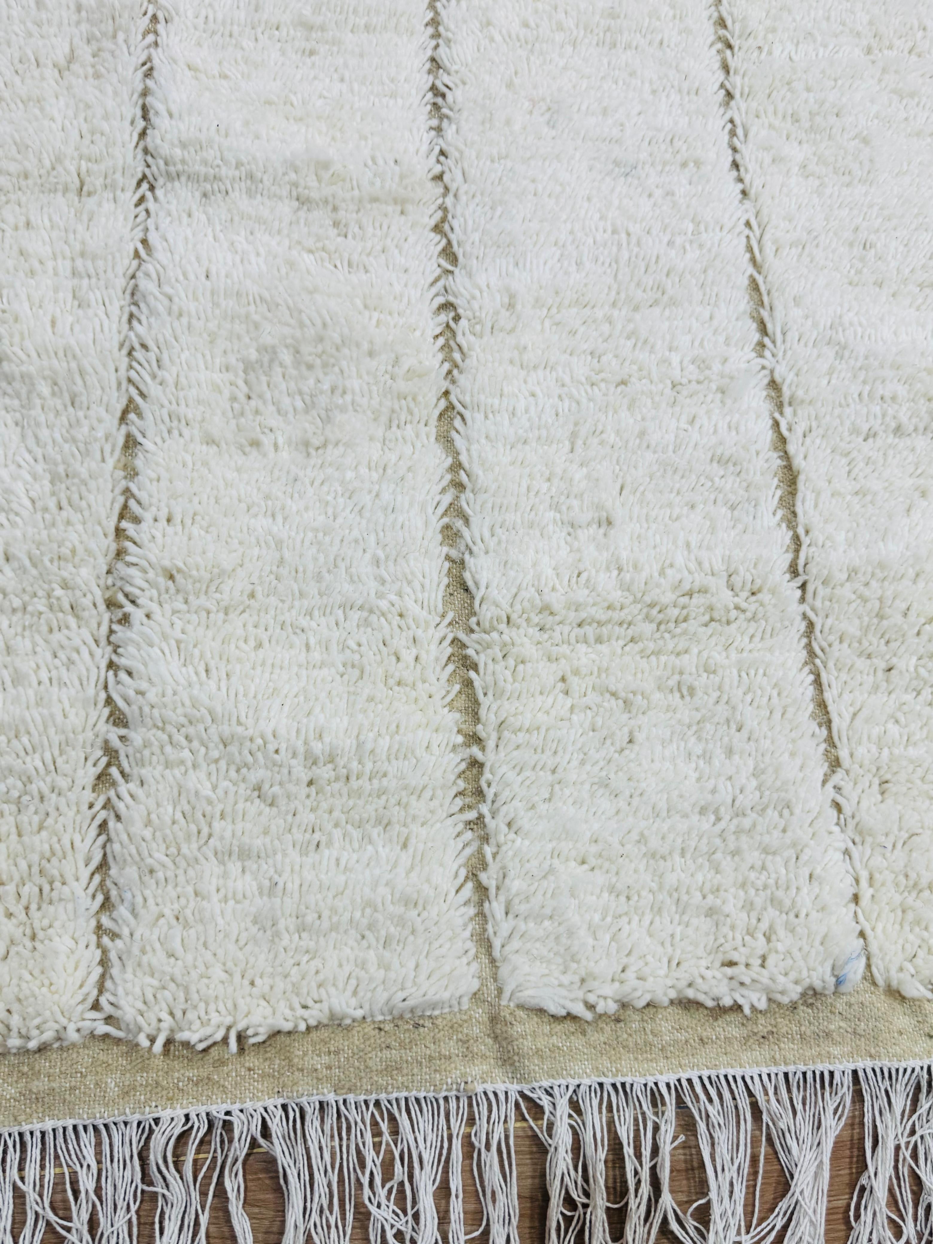 Close-up of Tazgart cream wool rug with raised linear texture and fringe edges.