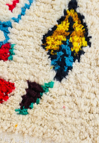 Close-up of hand-knotted fringe and vibrant geometric patterns on an artisan Moroccan rug.