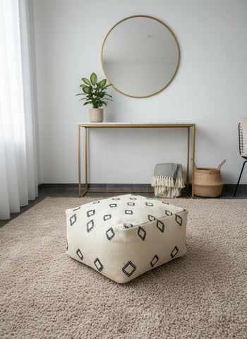 Cream Moroccan pouf with black tribal squares in minimalist living room.