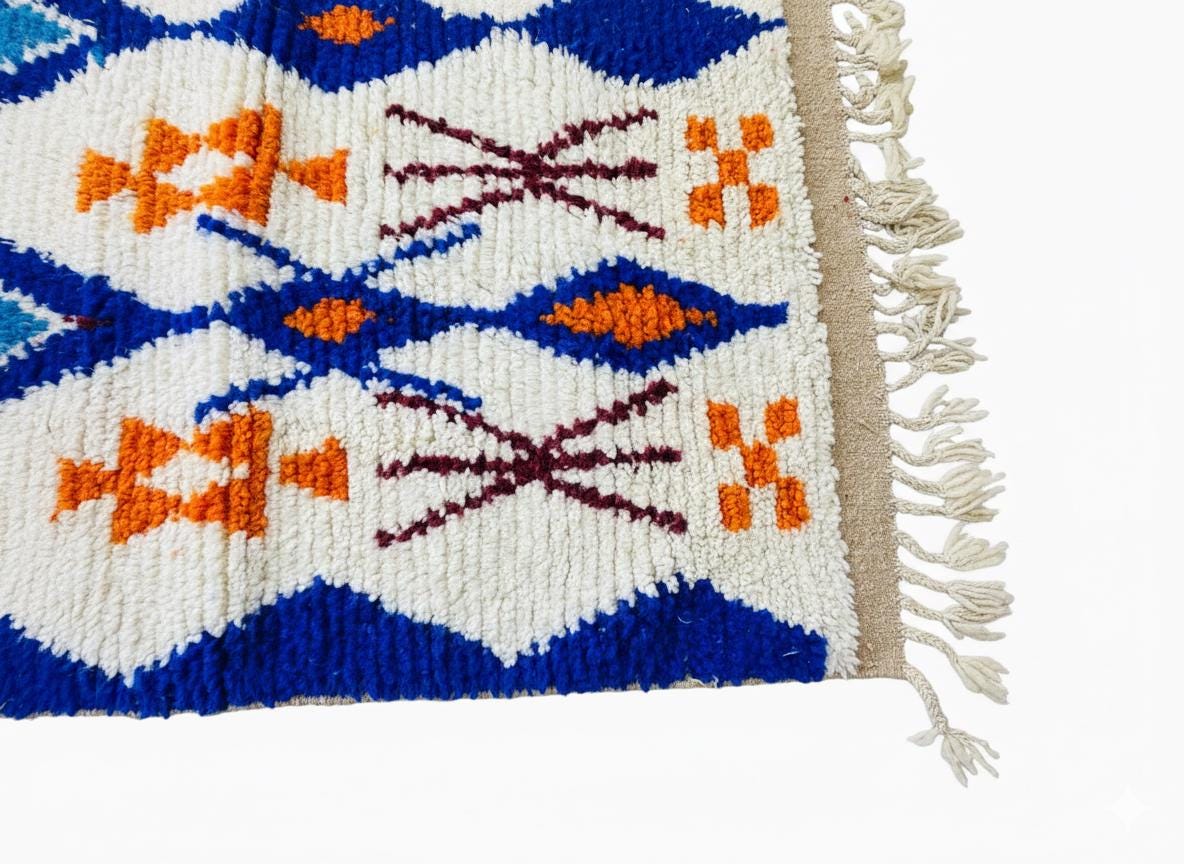 Colorful Moroccan runner rug with blue and orange geometric motifs on a cream background, finished with hand-knotted fringe.