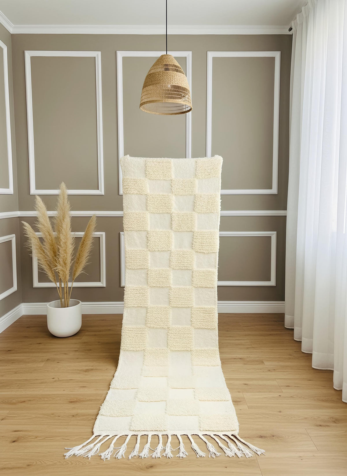 Handmade ivory runner rug with checkerboard texture displayed vertically under a woven pendant light in a warm-toned room.