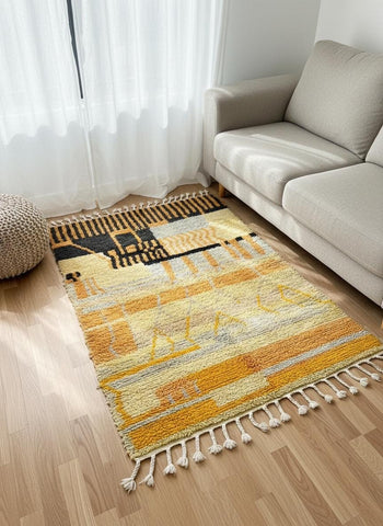 Berber wool area rug in yellow and black placed beside beige sofa.