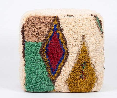 Close-up of a Moroccan Berber pouf showcasing thick wool pile, intricate geometric motifs, and artisan craftsmanship.
