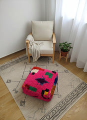 Mazin fuchsia pouf styled in a cozy reading corner.