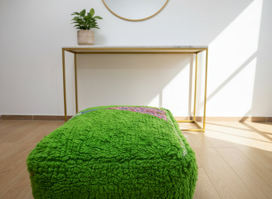 Green Berber wool pouffe in a modern interior under natural light.