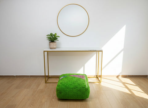 Green Berber pouffe placed in a bright minimalist room.