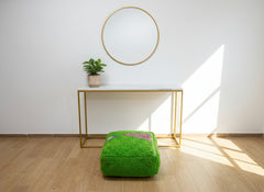 Green Berber pouffe placed in a bright minimalist room.