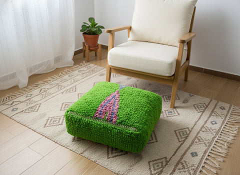 Handwoven green Moroccan pouffe in a cozy boho reading corner.