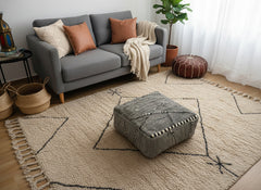 Black and cream Berber Tamazirt pouf on a beige Moroccan rug.