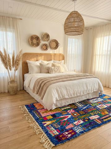 Colorful Moroccan rug under neutral bedroom decor.