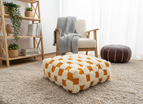 Checkered Berber pouffe beside a wooden chair and plants.