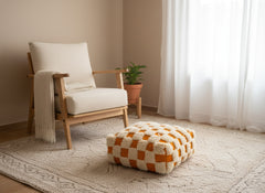 Handmade orange and cream pouffe on a textured rug in a warm space.