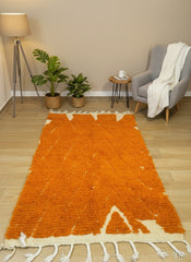 Handwoven Tanouba Berber orange rug with cream fringe displayed in modern living room