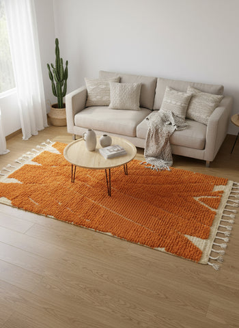 Bright orange Moroccan wool rug with geometric details under beige sofa and round table