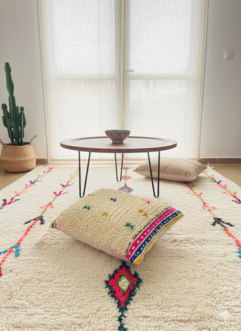 Living room with a colorful rug, coffee table, and decorative pillow.