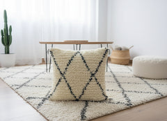 Titrit Berber pillow styled on cream rug in bright modern living room