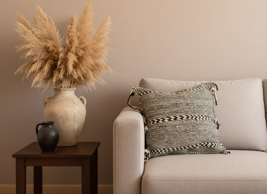 Tisra Berber pillow styled on beige sofa with ceramic vase and pampas grass